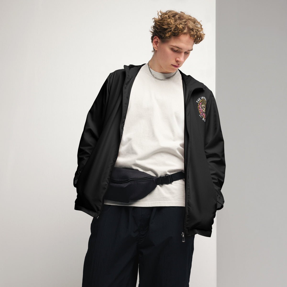 A man posing with an open jacket with The Immortal Society logo.