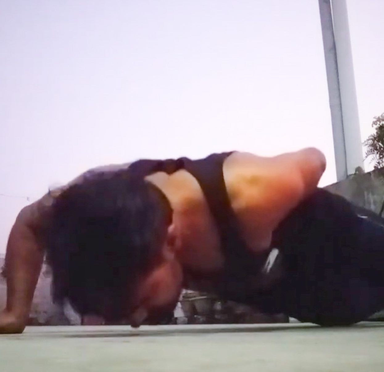A man going down on the push up position while he is wearing a black tank top with The Tattooed Ronin design. 